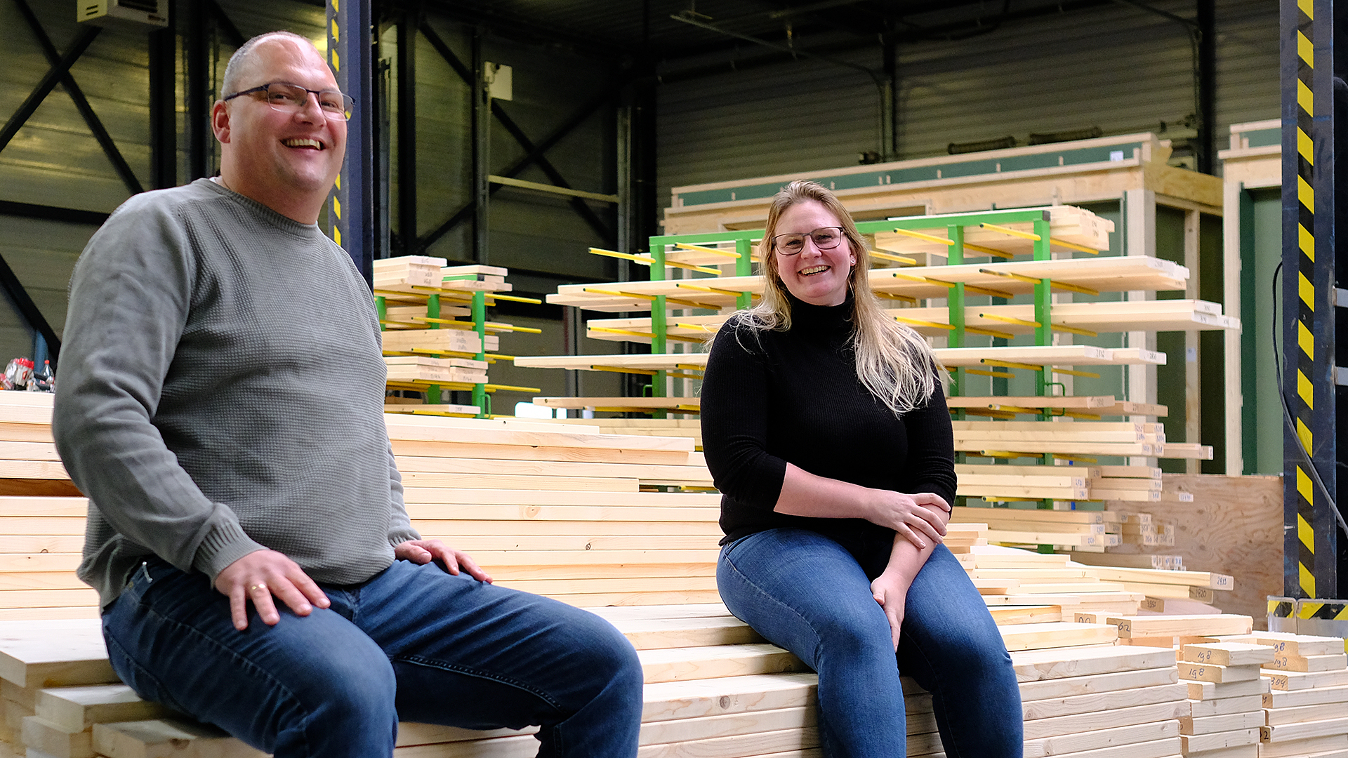 Projectleider Steven en werkvoorbereider Jeanine poseren op een stapel hout